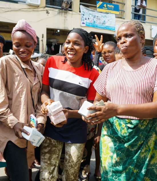 Three smiling women holding a pad, symbolizing empowerment and the fight against period poverty in Lagos.